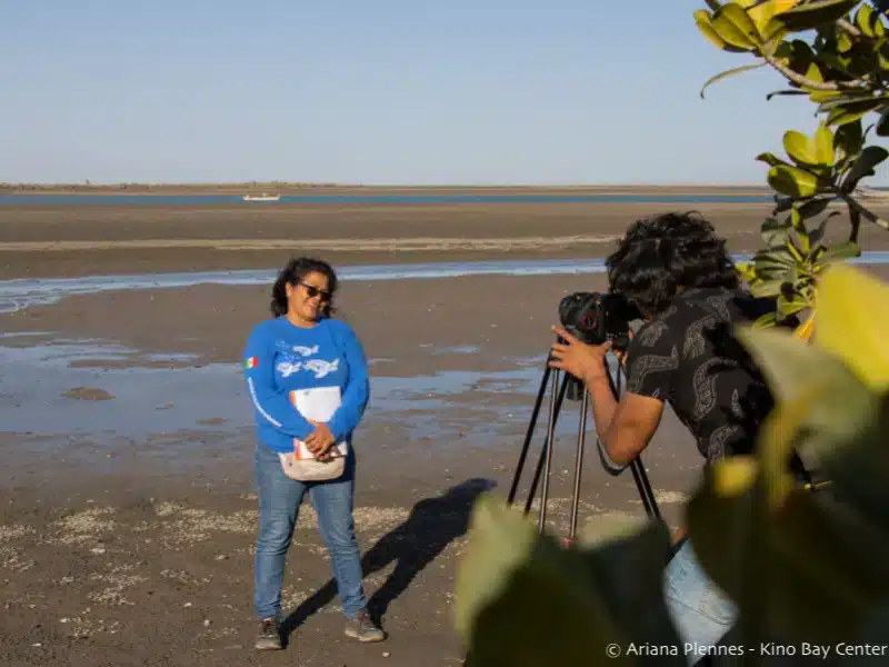Hombre tomando una foto de una mujer de pie en la playa.